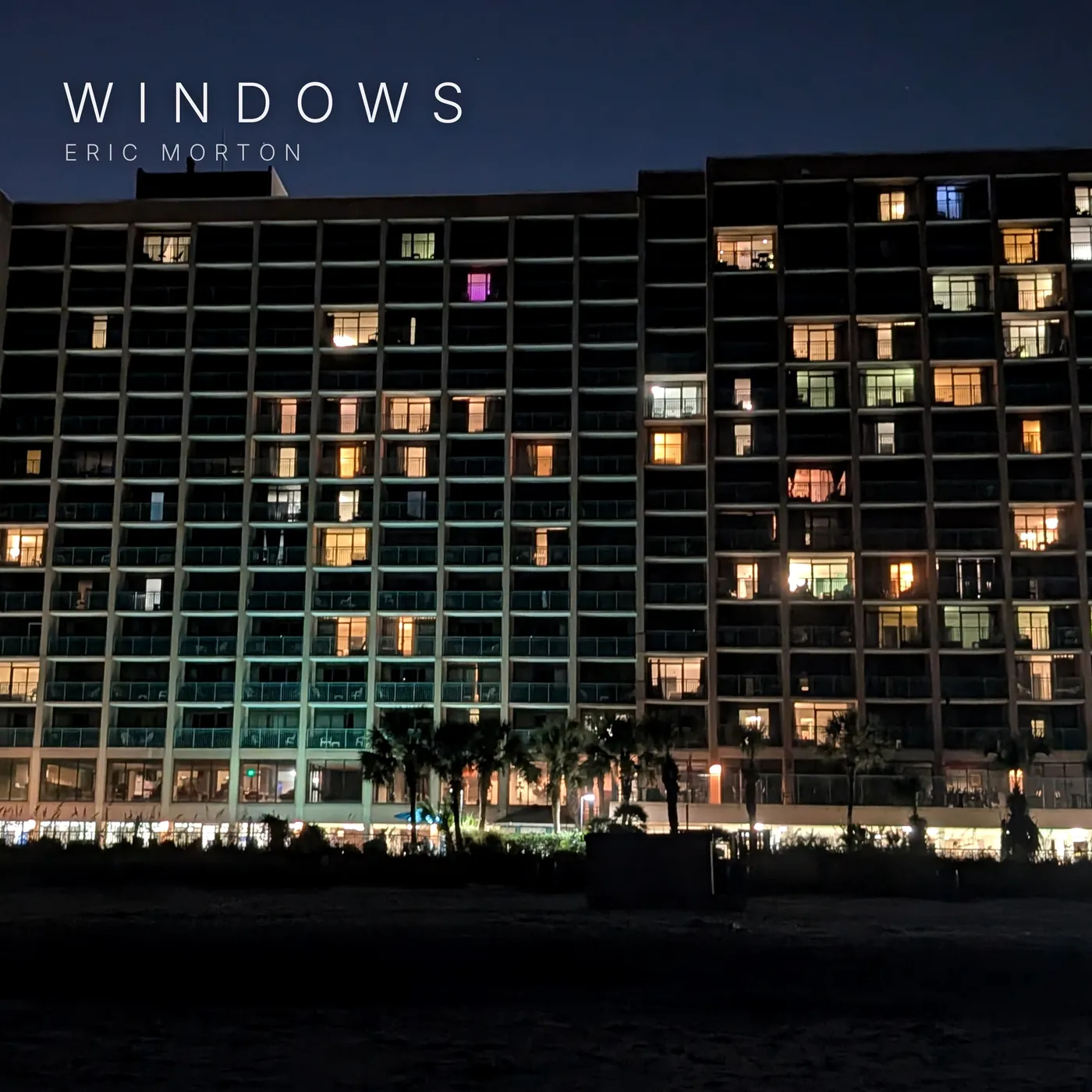 Windows cover art: a beachfront high-rise at night, its windows lit one by one